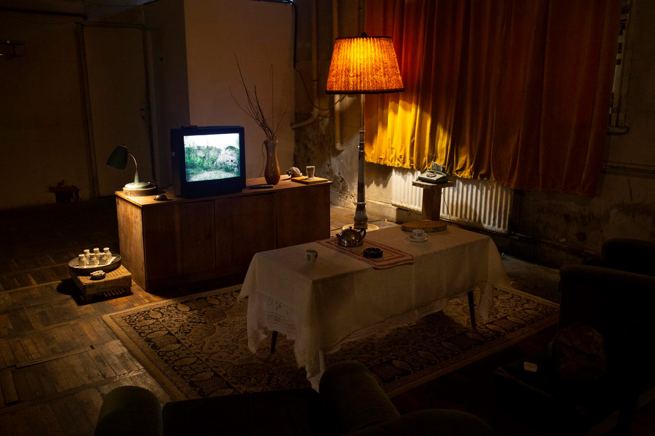 Dark room lit by a lamp and an old tv set. 